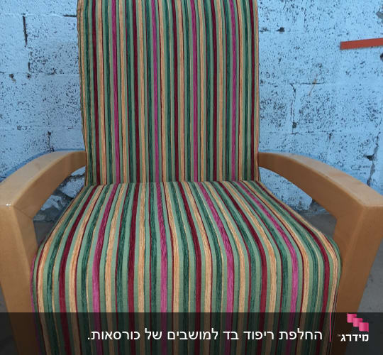 כיסא מרופד בפסים צבעוניים על רקע קיר בטון